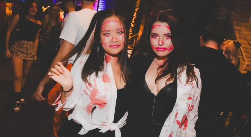 Zwei Frauen mit gruseligen Halloween-Schminkereien und blutigen Outfits feiern in der Halle Tor 2.