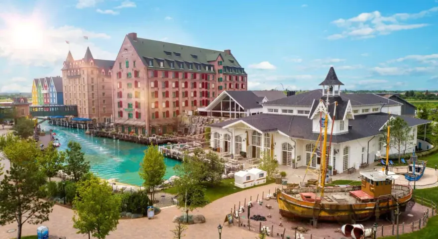 Ein malerischer Kanal fließt vorbei an bunten Gebäuden und einem alten Schiff. Das ist das charmante Themenhotel im Europa-Park.