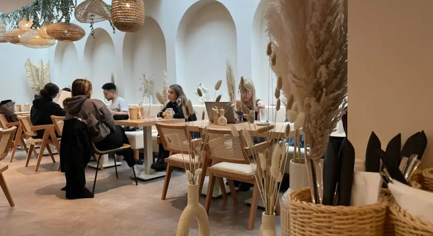 Gemütliches Café mit Boho-Deko, geflochtenen Lampen und Trockenblumen. Gäste genießen ihren soul brunch in entspannter Atmosphäre.