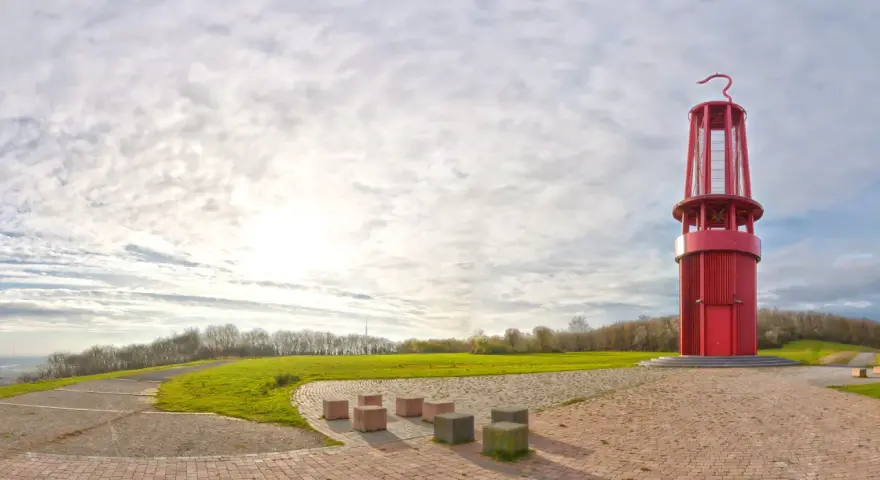 Rote Aussichtsturm auf der Halde Moers, umgeben von grünen Hügeln und einem weiten Himmel mit Wolken.