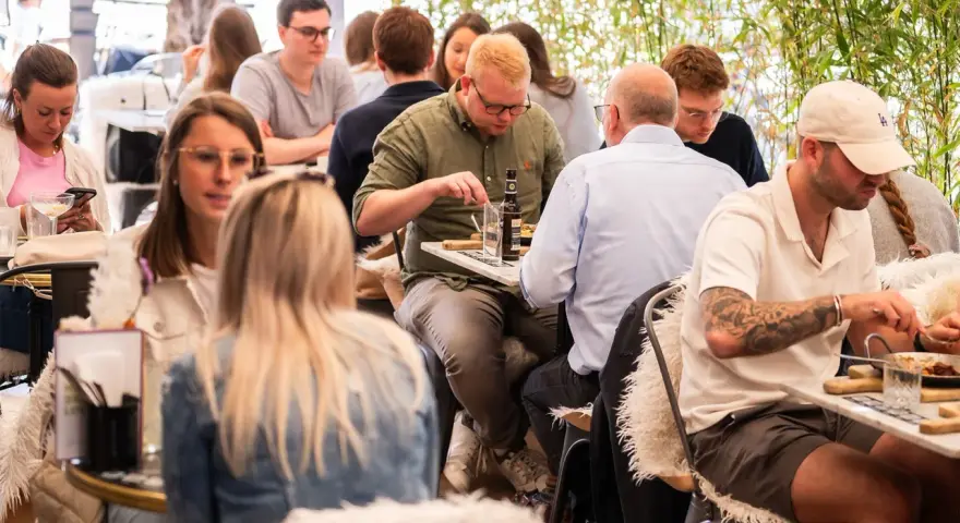 Leute genießen ein entspanntes St. Louis Frühstück im Freien, umgeben von Grün.