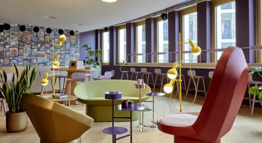 Ein bunter, moderner coworking space cologne mit auffälligen Möbeln, Comic-Wand und gelben Stehlampen.