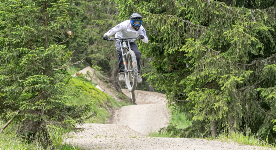 Mountainbiker springt über eine Schanze im Wald. Die **Halde Hoppenbruch** bietet eine tolle Kulisse für diesen Sprung.