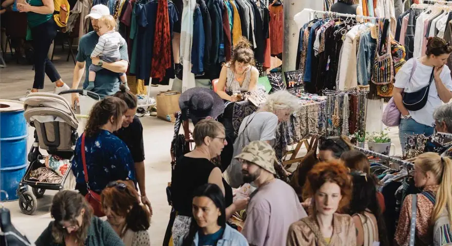Menschen stöbern auf einem belebten **bazar de nuit** nach Kleidung und Accessoires.