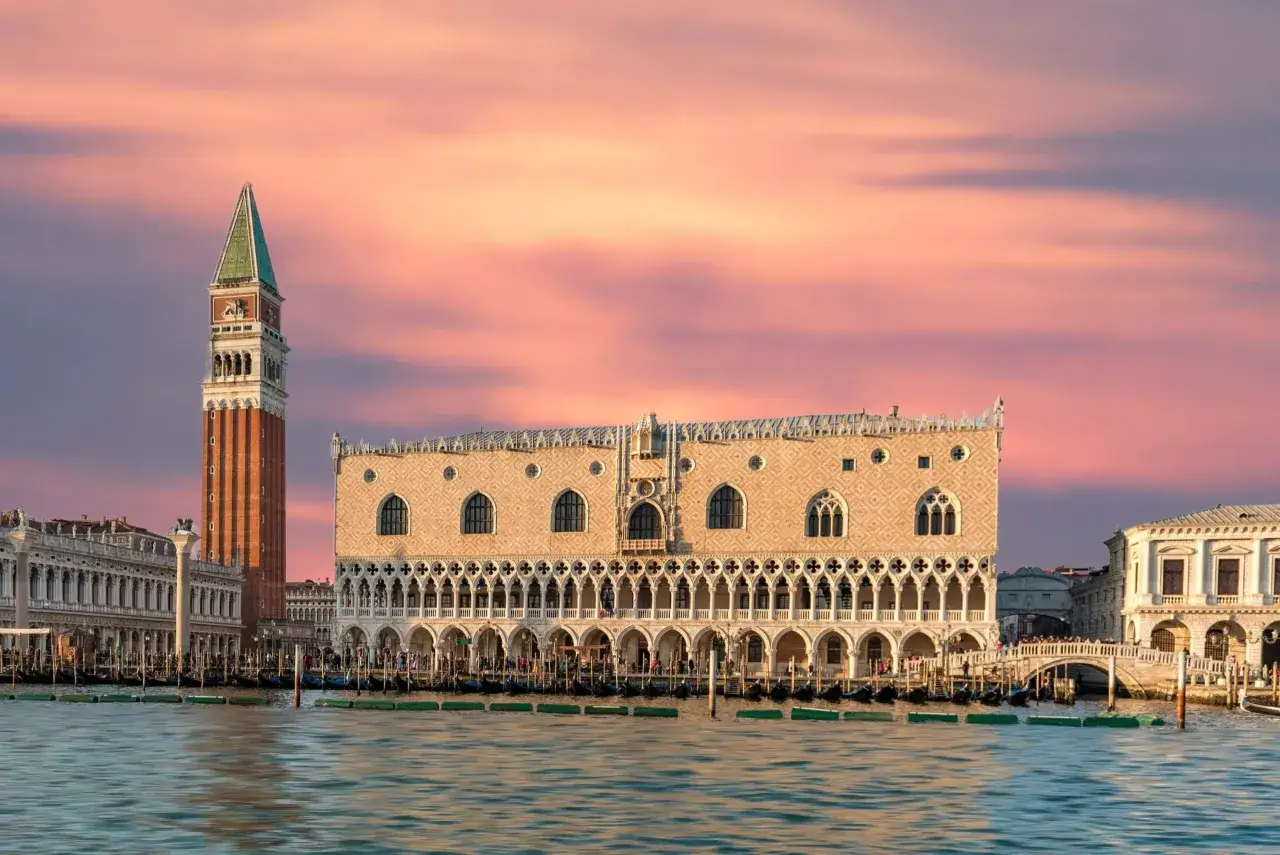 Der Dogenpalast und der Campanile am Markusplatz sind ein Muss, wenn man in Venedig ist. Gondeln liegen im Wasser vor den prächtigen Gebäuden.