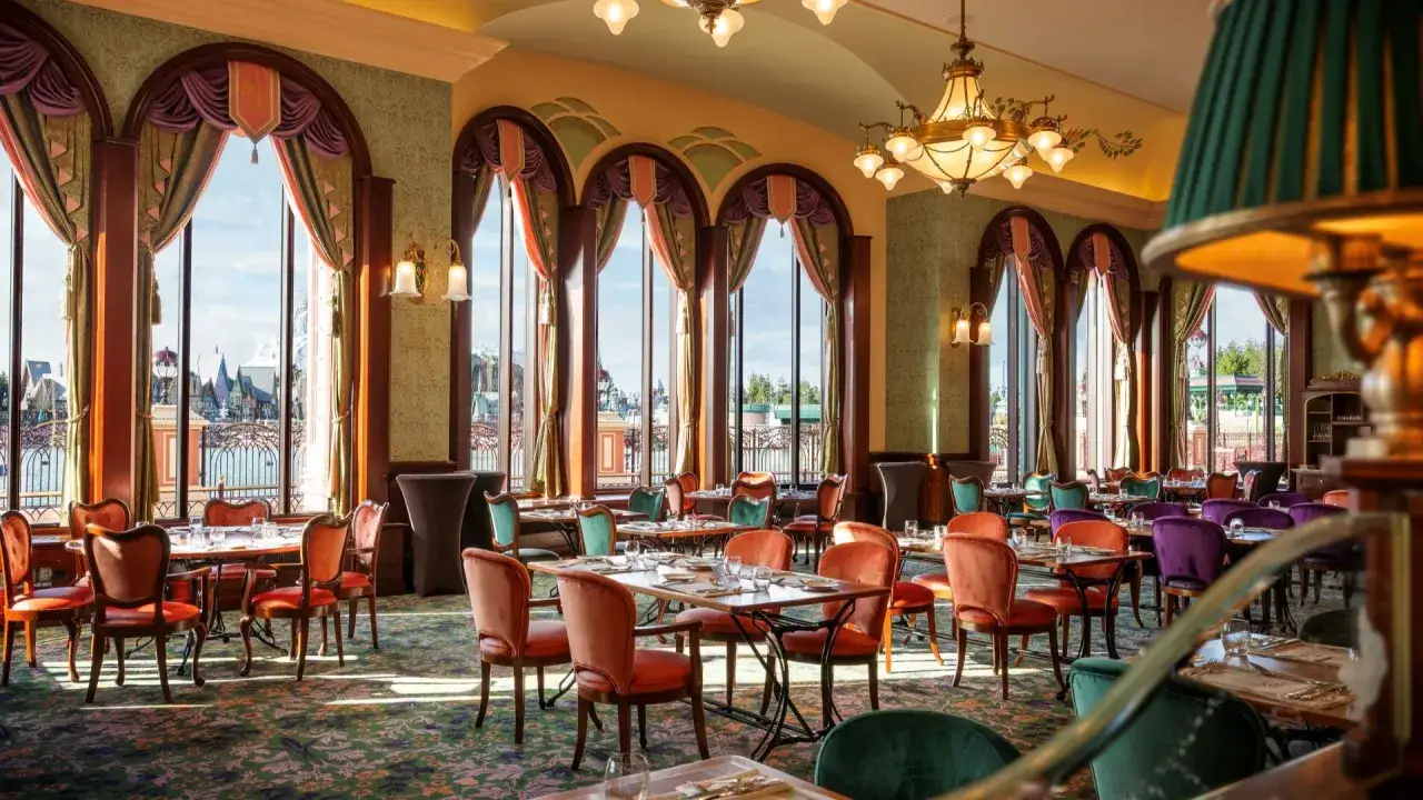 Elegantes Restaurant im Disneyland Paris mit Blick auf den Park. Bunte St&uuml;hle und &uuml;ppige Vorh&auml;nge schaffen eine magische Atmosph&auml;re.