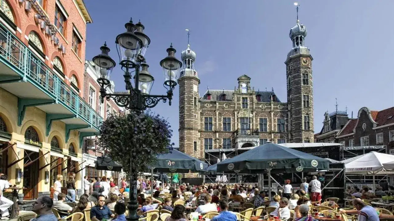 Lebhafter venlo markt mit vielen Menschen, die drau&szlig;en sitzen. Im Hintergrund das historische Rathaus.