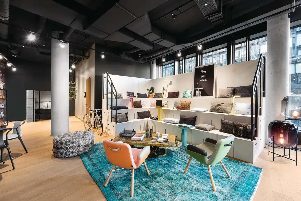 Gem&uuml;tlicher coworking space cologne mit Sitzstufen, Kissen, Fahrr&auml;dern und stilvollen Lampen.