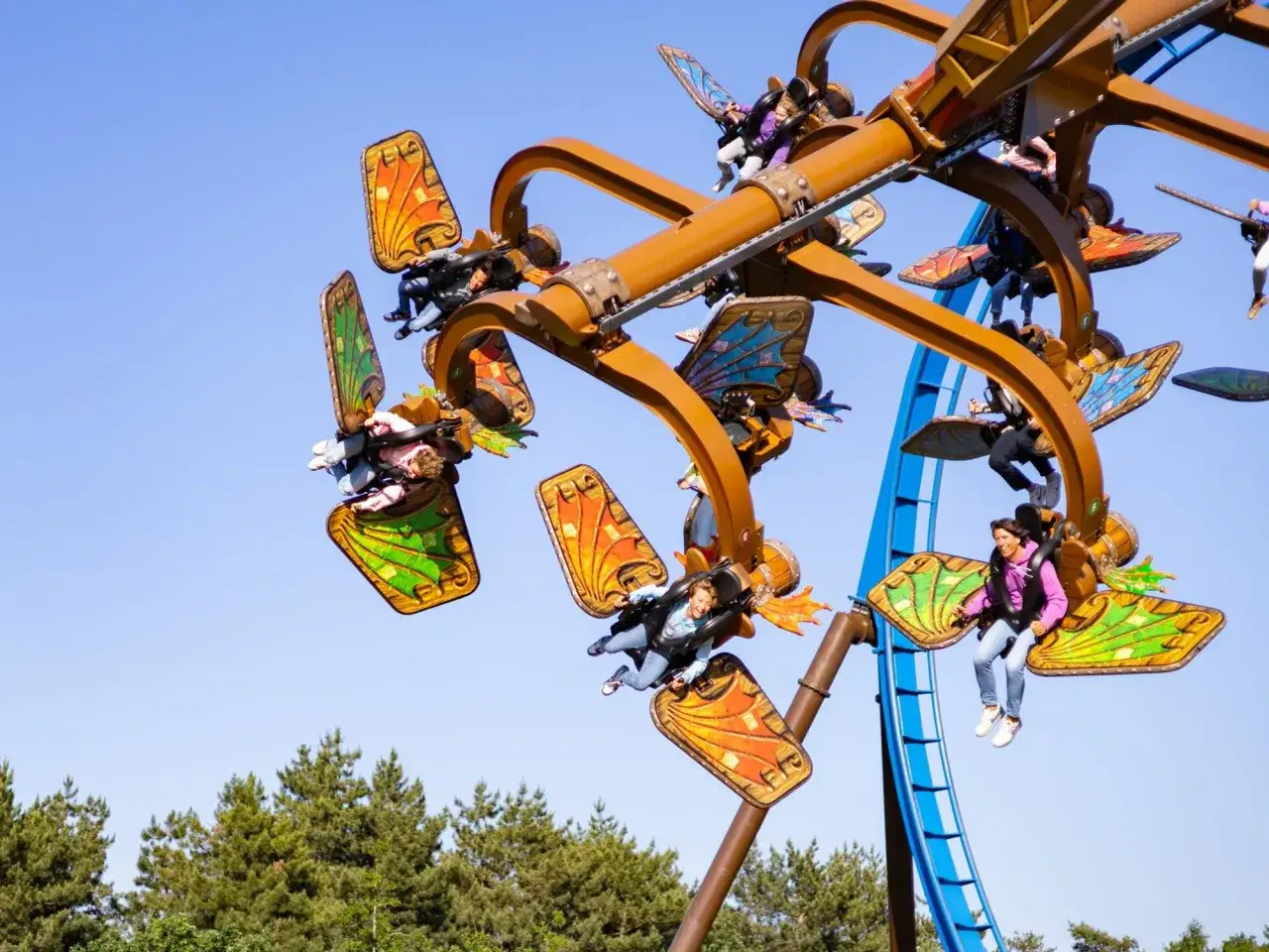 Flug durch den Himmel im Toverland Freizeitpark! Kinder und Erwachsene genie&szlig;en die Fahrt auf einer bunten Attraktion mit Schmetterlingsfl&uuml;geln.