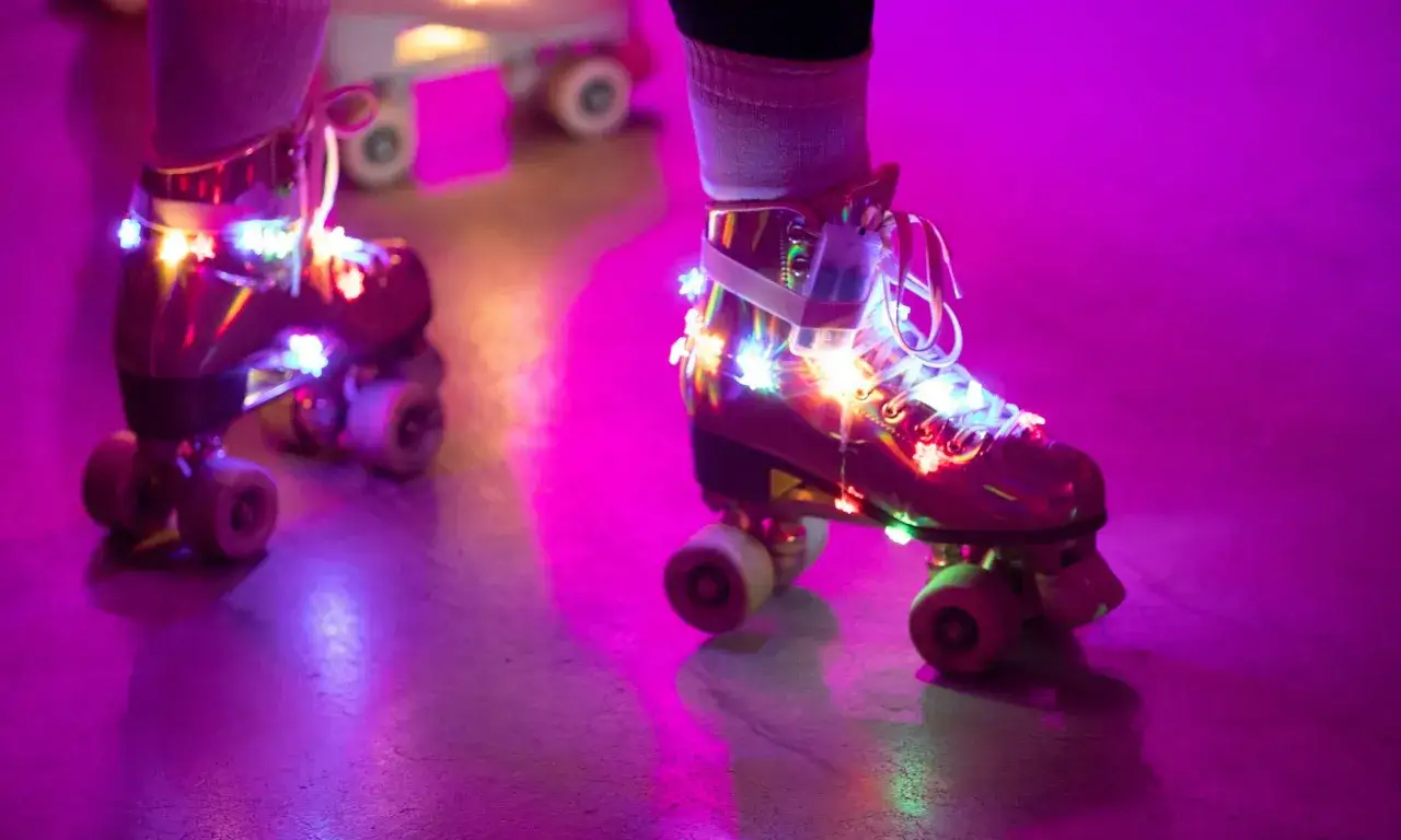 Bunte Lichter schmücken Rollschuhe auf einer Zollverein Rollschuhbahn im lila Schein.