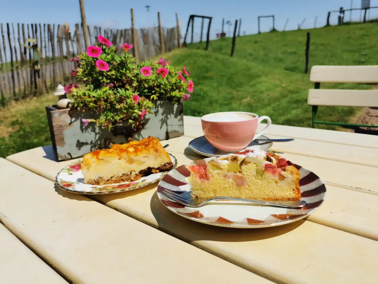 Zwei St&uuml;cke Kuchen und ein Kaffee auf einem Tisch im Freien. Ein Genuss im Kuchen Cafe.