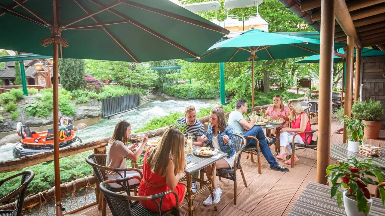 G&auml;ste genie&szlig;en im Restaurant im Europa-Park ein Essen mit Blick auf eine Wildwasserbahn.