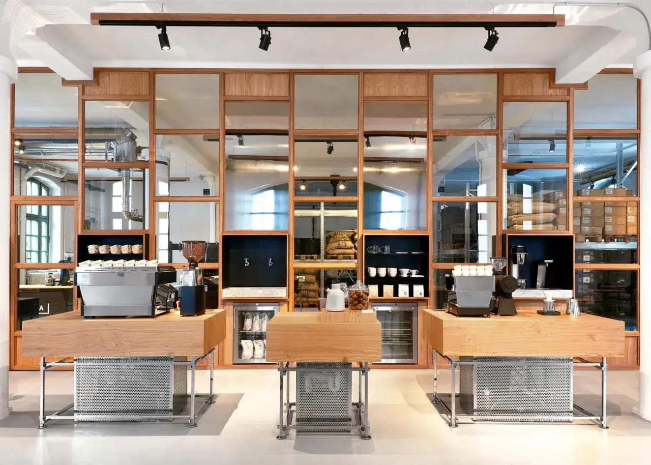 Moderne Einrichtung im Copenhagen Coffee Lab mit Holz und Spiegeln. Kaffeemaschinen, Bohnen und Tassen sind ausgestellt.