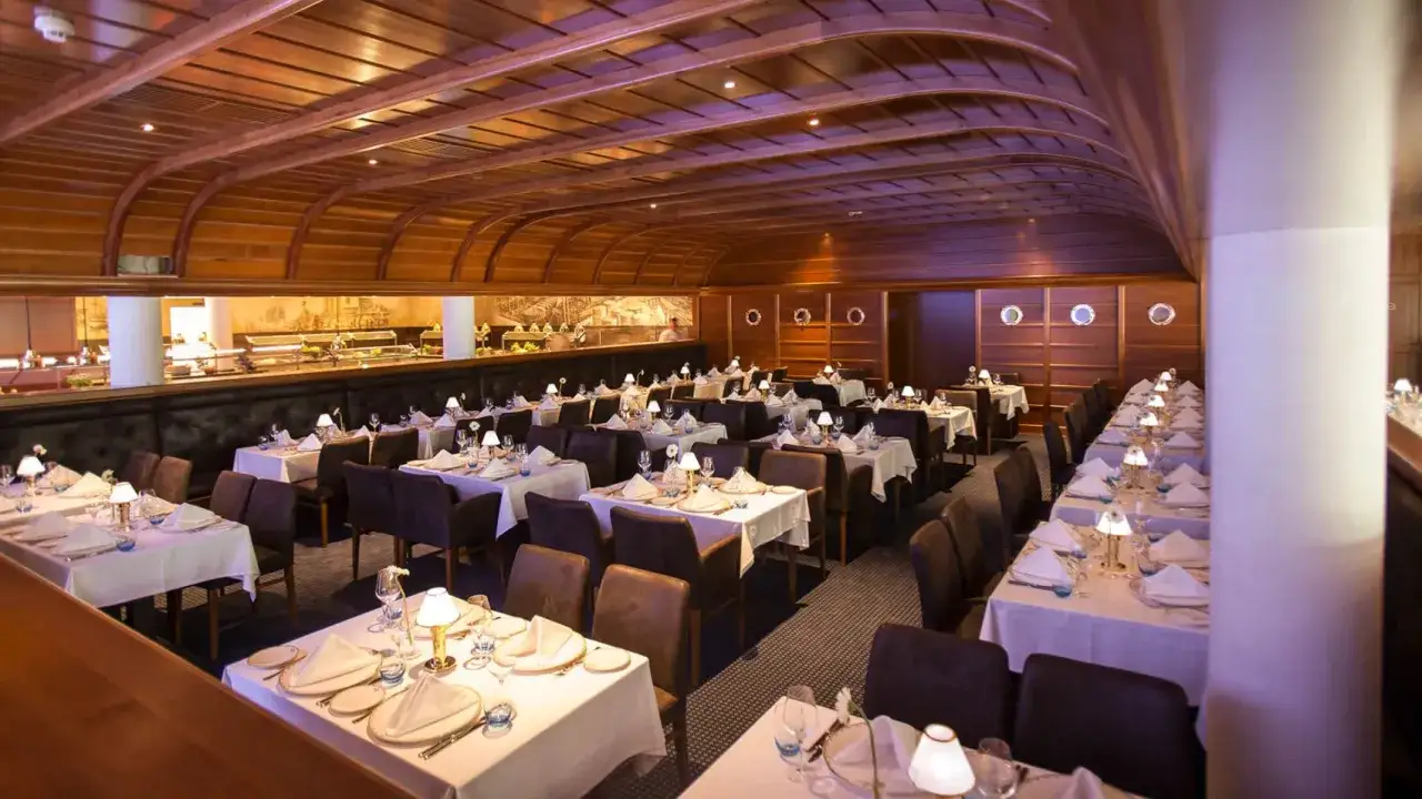 Elegantes Restaurant mit vielen gedeckten Tischen, Holzwänden und Bullaugen. Hier könnte die Bell Rock Restaurant Speisekarte für ein festliches Mahl liegen.