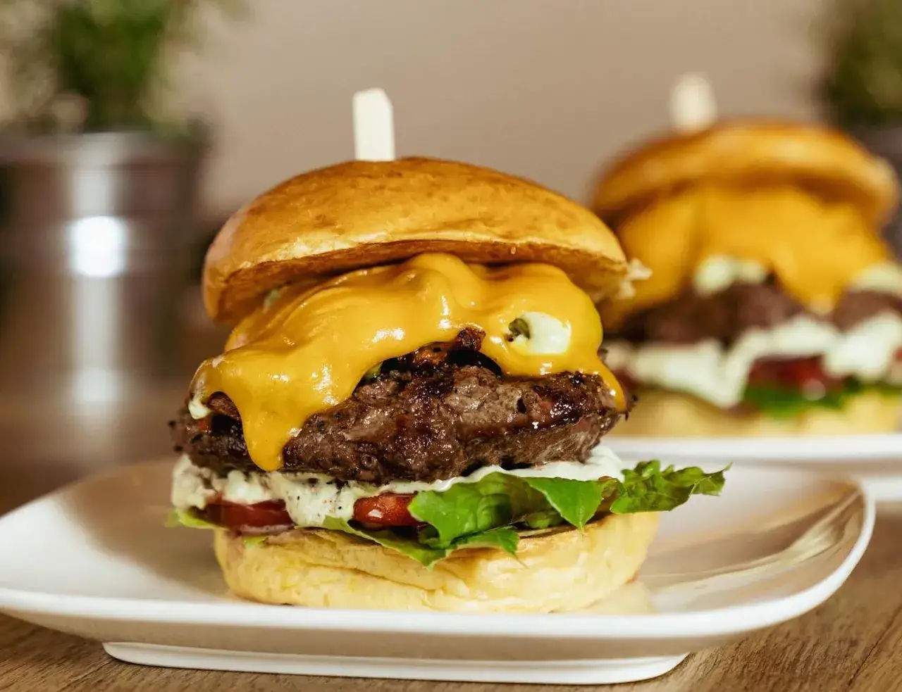 Saftiger Burger mit geschmolzenem K&auml;se, Salat und Tomate. Der beste Burger in K&ouml;ln, der auf einem Teller serviert wird.