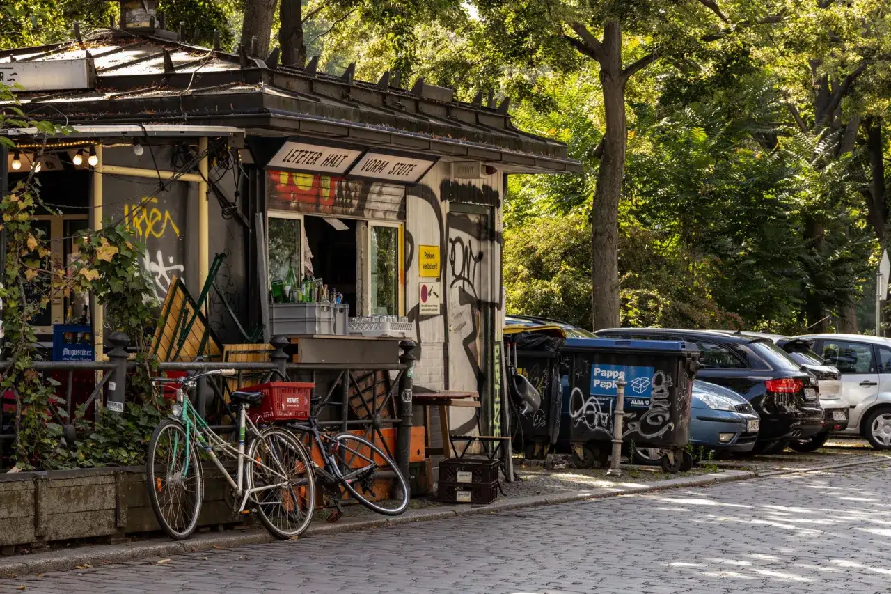 Ein Kiosk mit Graffiti in Berlin Kreuzberg, Fahrräder und Autos parken davor.