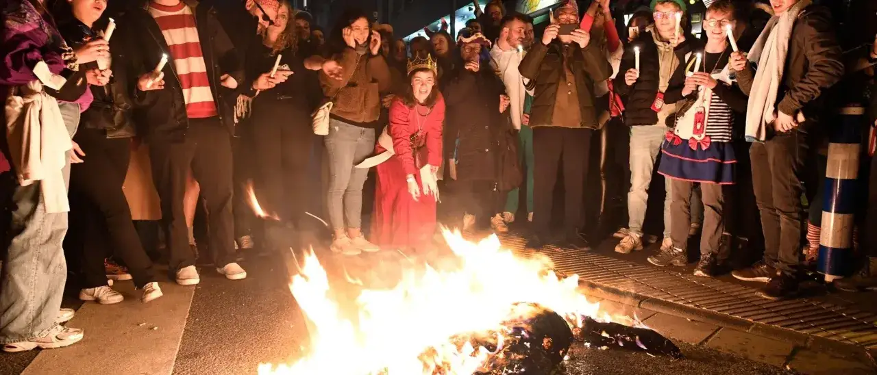 Eine Gruppe Menschen mit Kerzen umringt ein Feuer. Eine Frau mit Krone feiert mit. Wann wird der Nubbel verbrannt? Heute Nacht!