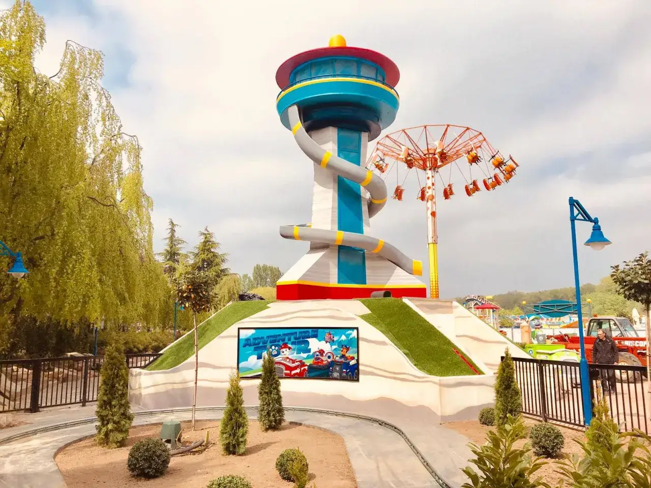 Der Paw Patrol Tower im Nickelodeon Park Deutschland lädt zu Abenteuern ein. Ein Kettenkarussell dreht sich im Hintergrund.