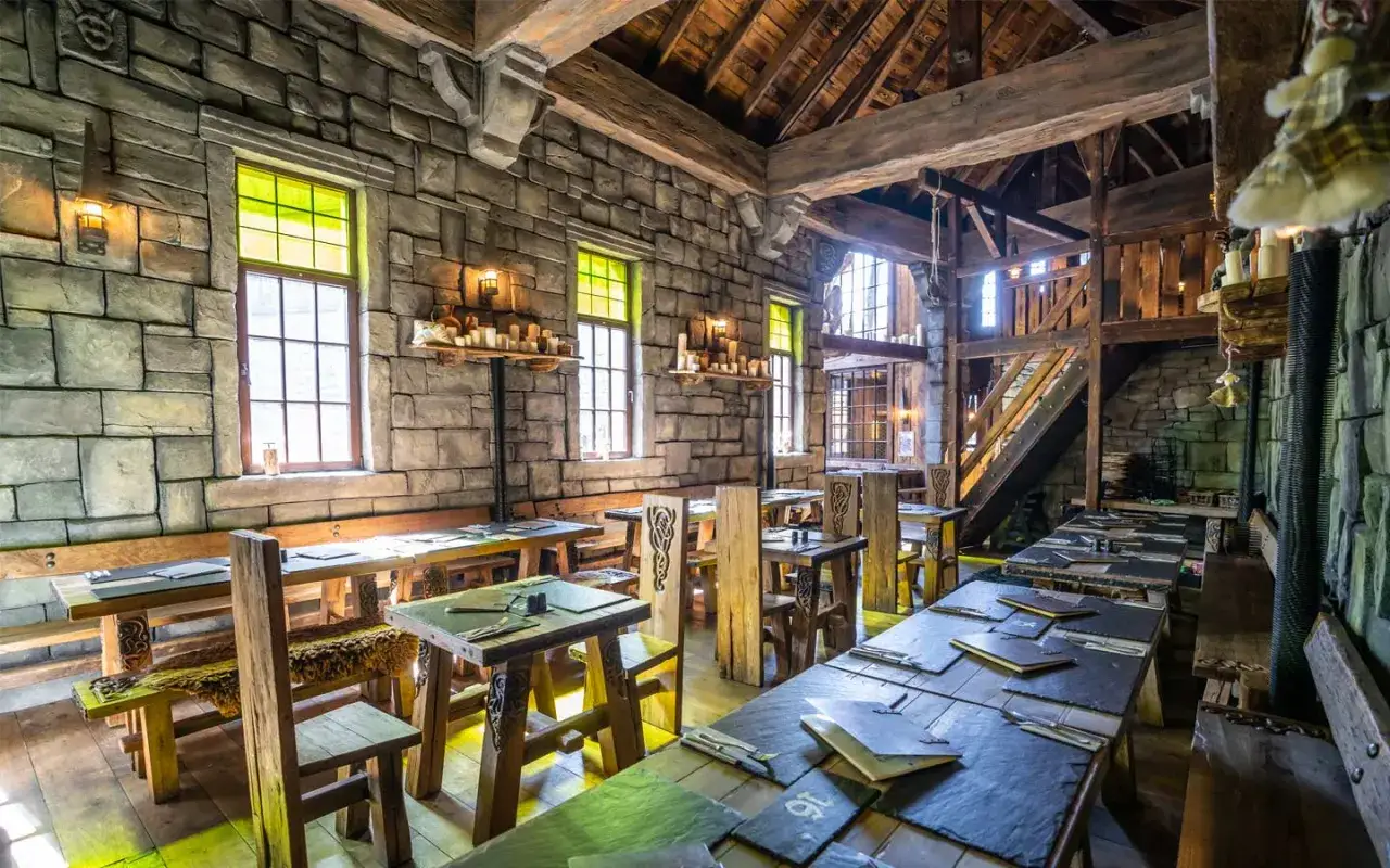 Rustikale Phantasialand Taverne mit Steinw&auml;nden, Holzbalken und urigen Tischen, bereit f&uuml;r G&auml;ste.