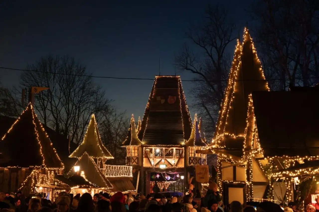 Der kleinste Weihnachtsmarkt der Stadt leuchtet im Dunkeln. Fachwerkhäuser mit spitzen Dächern sind mit Lichterketten geschmückt, Menschen drängen sich auf dem Platz.