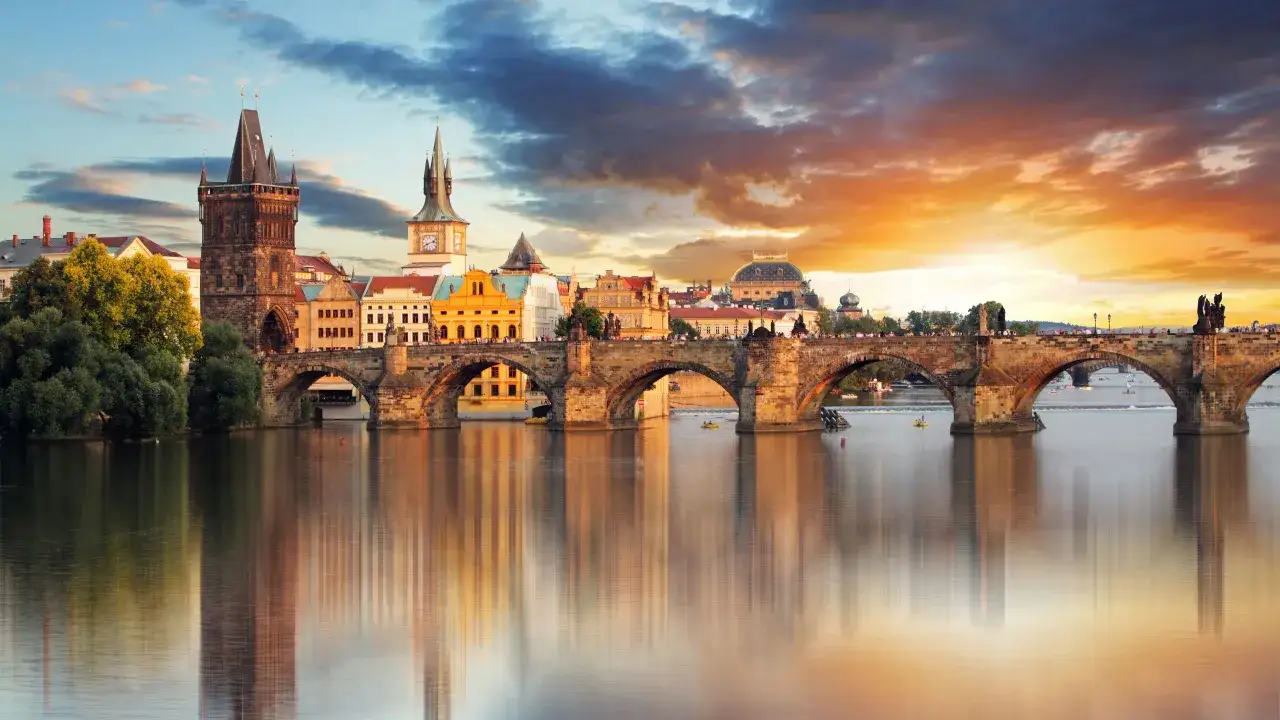 Karlsbrücke in Prag bei Sonnenuntergang, ein Wahrzeichen der Stadt. Die Spiegelung der Brücke und der Gebäude im Wasser ist ein Highlight.