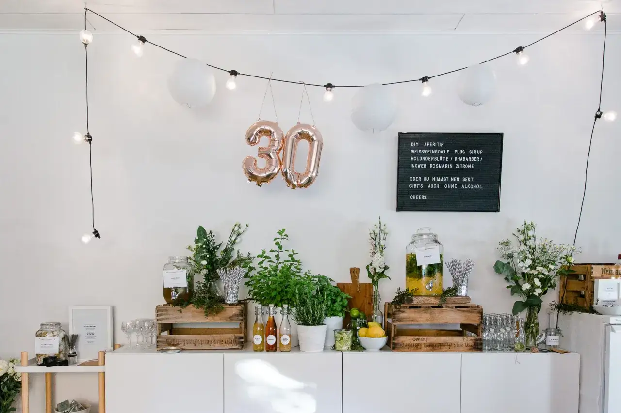Luftballons in Form der Zahl 30 schweben &uuml;ber einer Getr&auml;nkebar mit frischen Kr&auml;utern und Zitrusfr&uuml;chten. Perfekt, um den 30. Geburtstag zu feiern!