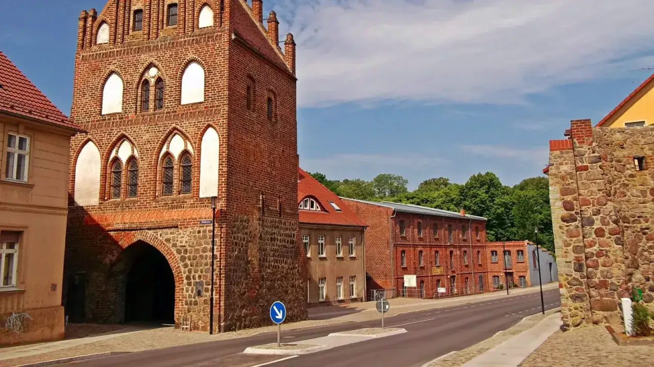 Historisches Stadttor in Templin Altstadt, mit Backsteinfassade und steinernem Sockel. Dahinter rote Backsteingeb&auml;ude und gr&uuml;ne B&auml;ume.