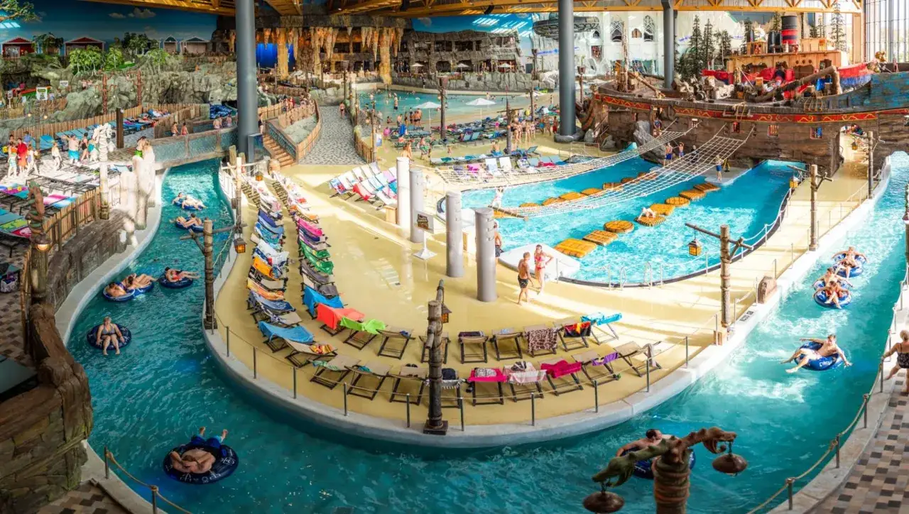 Ein tropischer Tag im Rulantica Wasserpark. Menschen entspannen auf Liegest&uuml;hlen und treiben auf Schlauchbooten im Wasser.