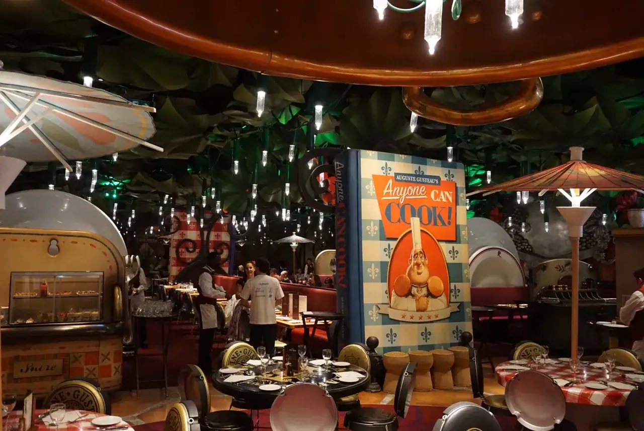 Im Inneren eines Ratatouille Restaurants in Paris steht ein riesiges Kochbuch mit Auguste Gusteau. Tische sind f&uuml;r G&auml;ste gedeckt.