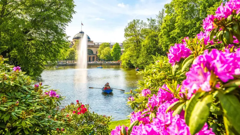Bootsfahrt auf dem See mit Brunnen im Hintergrund – eine schöne Idee für Wiesbaden Unternehmungen.