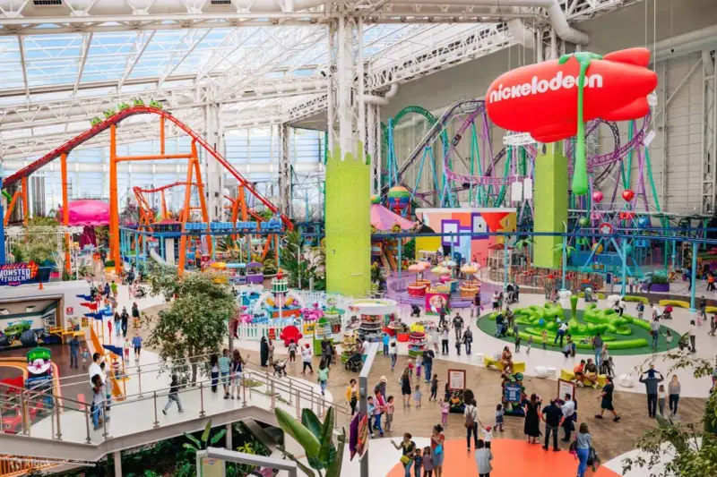 Buntes Treiben im Nickelodeon Park Deutschland mit Achterbahnen, Fahrgeschäften und vielen Besuchern.
