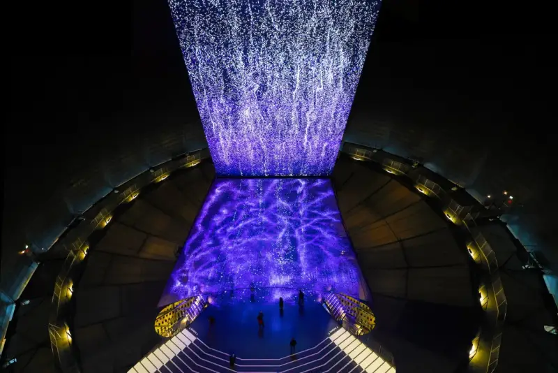 Im Gasometer Oberhausen erstrahlt eine Projektion aus tausenden Lichtpunkten, die wie ein Sternenhimmel oder ein Wasserfall wirken.