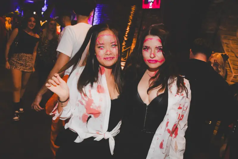 Zwei Frauen mit gruseligen Halloween-Schminkereien und blutigen Outfits feiern in der Halle Tor 2.