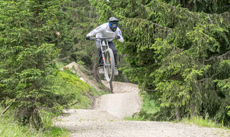 Mountainbiker springt über eine Schanze im Wald. Die **Halde Hoppenbruch** bietet eine tolle Kulisse für diesen Sprung.